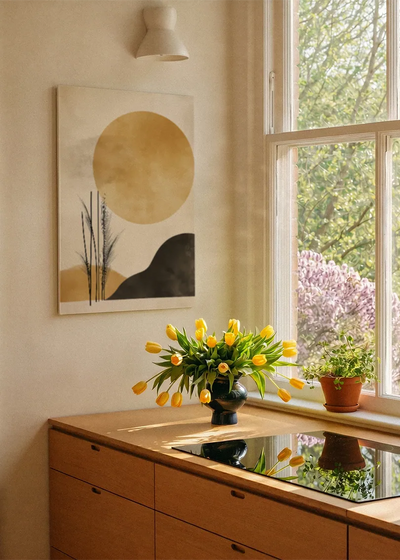 Akustikbillede med en gylden cirkel over en sort bakke med grene, ved et vindue med en blomsterbuket i karmen