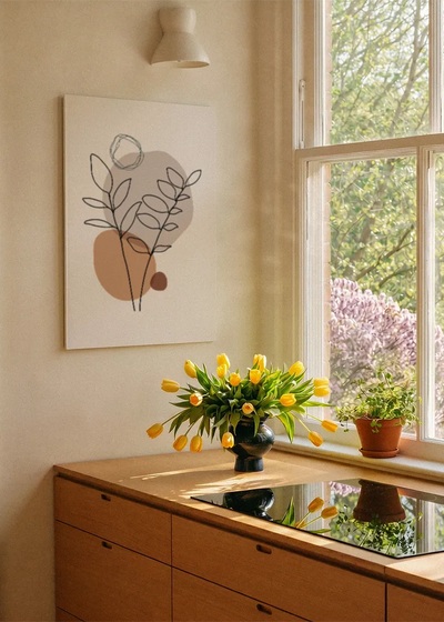Akustikbillede med en tegnet gren i en cirkelform, ved et vindue med en blomsterbuket i karmen