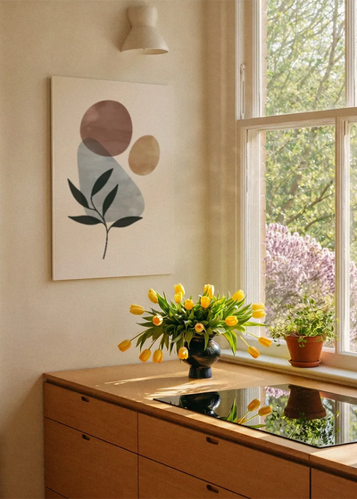 Akustikbillede med et grønt blad med grå og gyldne cirkler, ved et vindue med en blomsterbuket i karmen