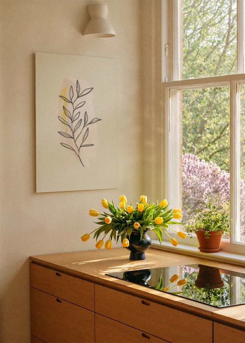 Akustikbillede med en gul gren med tegnede blade, ved et vindue med en blomsterbuket i karmen