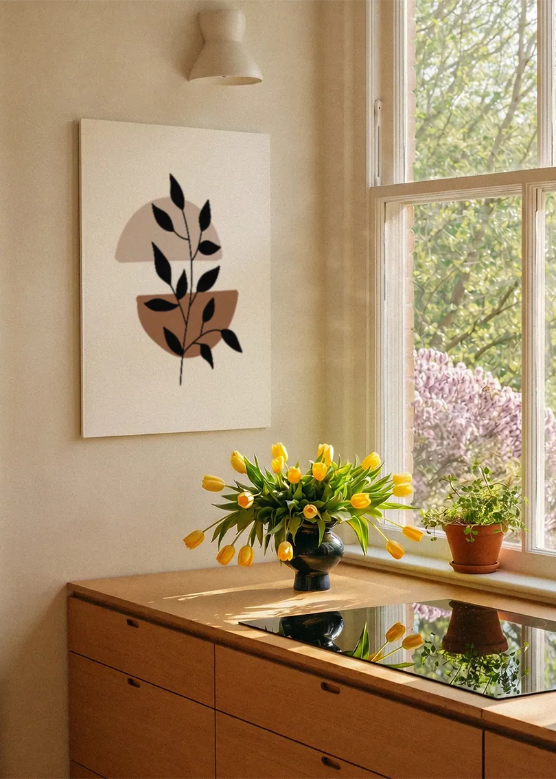 Akustikbillede med sorte blade på en brun form, ved et vindue med en blomsterbuket i karmen