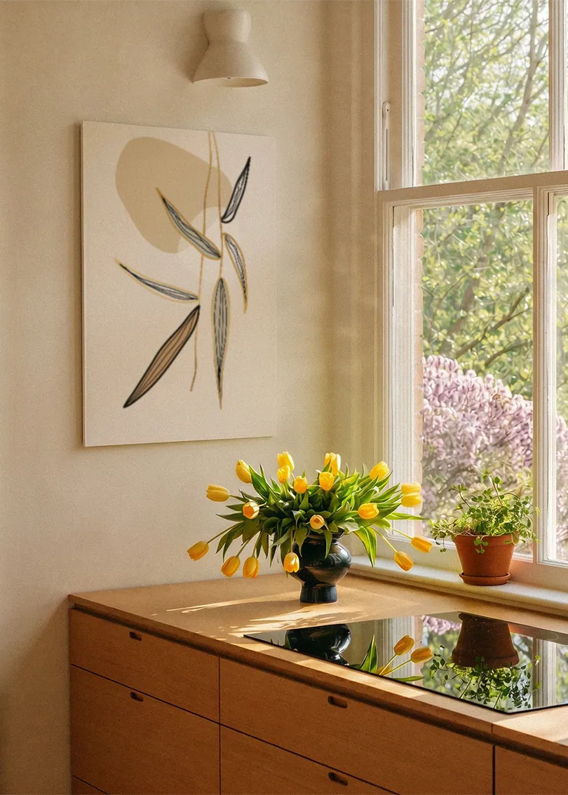 Akustikbillede med beige strå og blade, ved et vindue med en blomsterbuket i karmen