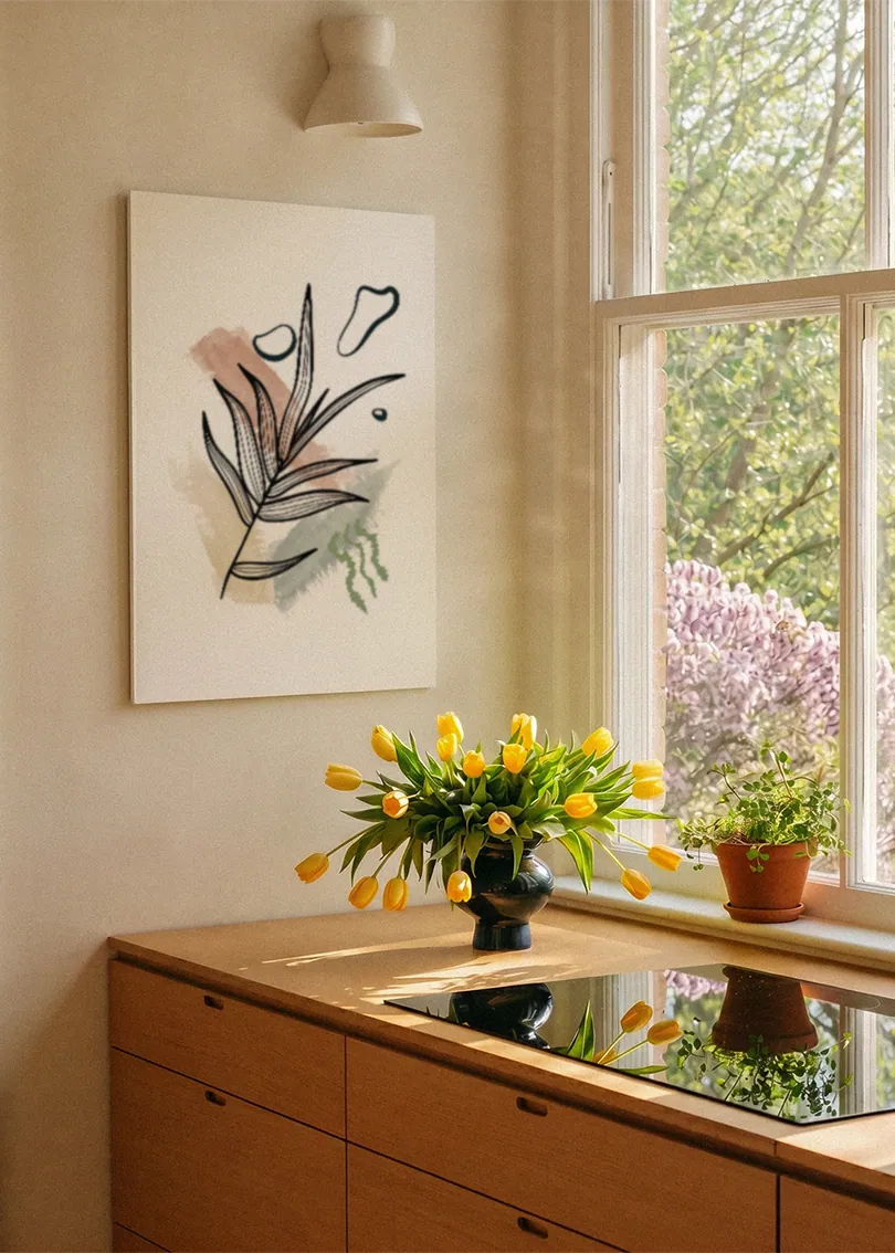 Akustikbillede med tegnede grene med lyserøde former, ved et vindue med en blomsterbuket i karmen