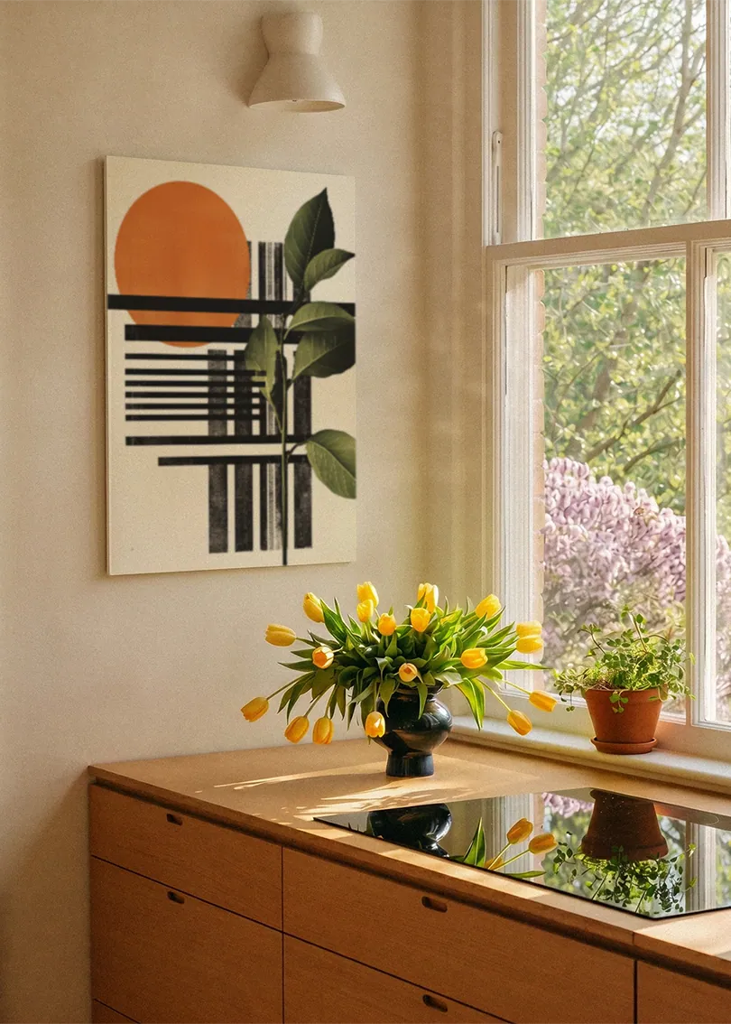 Akustikbillede med en orange cirkel med sorte striber og grønne blade, ved et vindue med en blomsterbuket i karmen