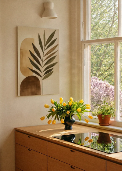 Akustikbillede med et stort grønt blad med beige former, ved et vindue med en blomsterbuket i karmen