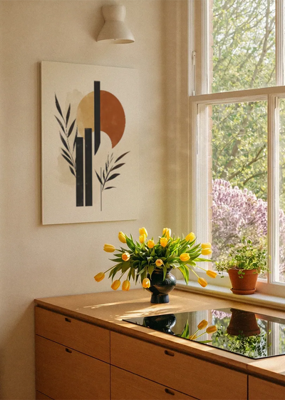 Akustikbillede med sorte blade foran en orange cirkel, ved et vindue med en blomsterbuket i karmen