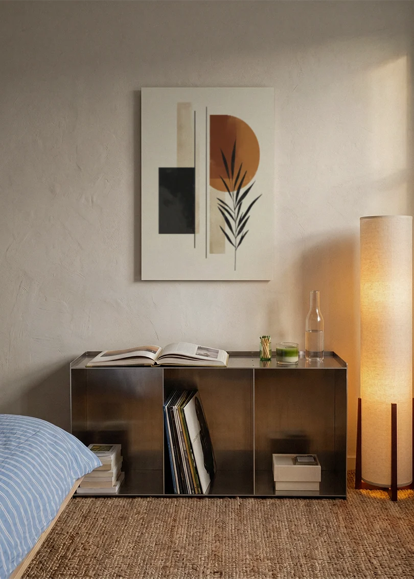 Akustikbillede med sorte og beige felter med et grønt blad, over sengegavlen i et soveværelse med tændt lampe