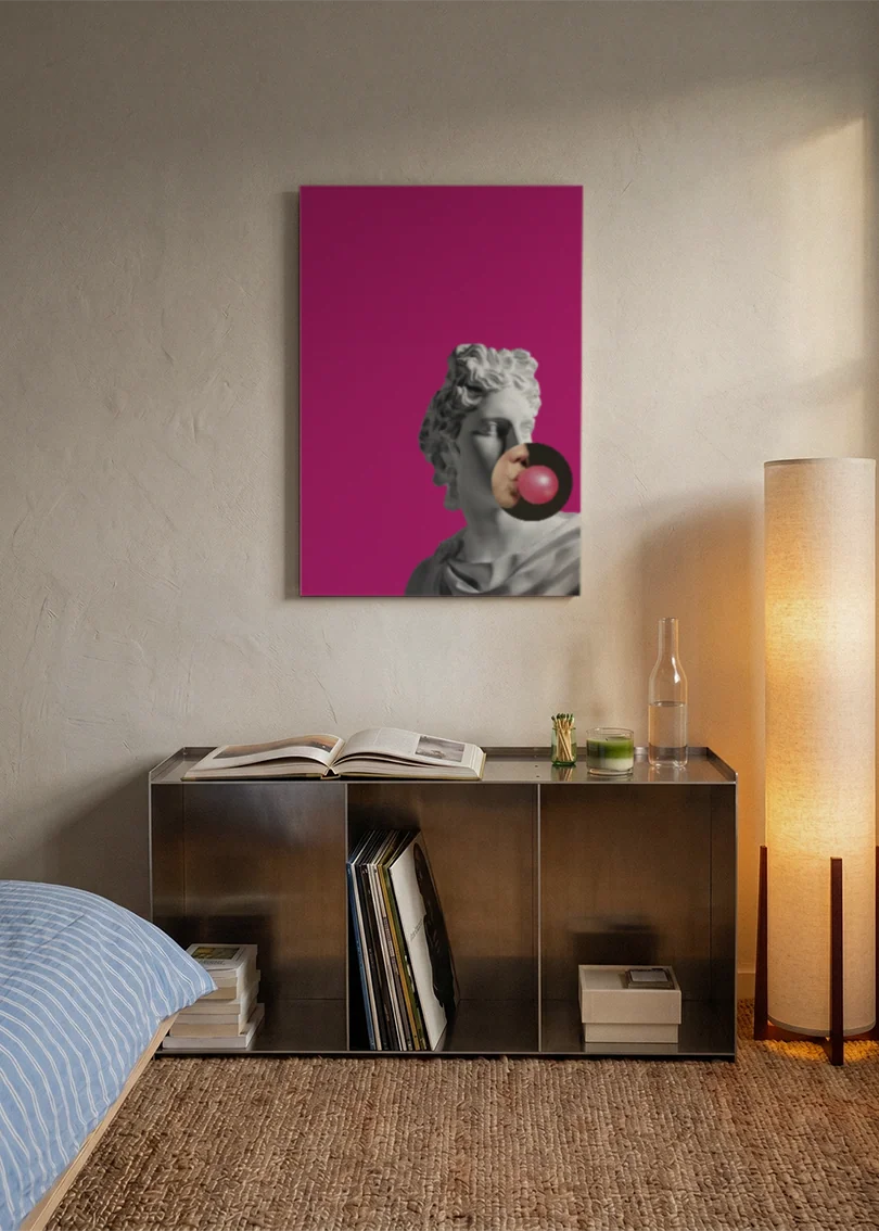 Akustikbillede med en gipsbuste med en tyggegummiboble på pink baggrund, over en reol i et soveværelse med tændt gulvlampe