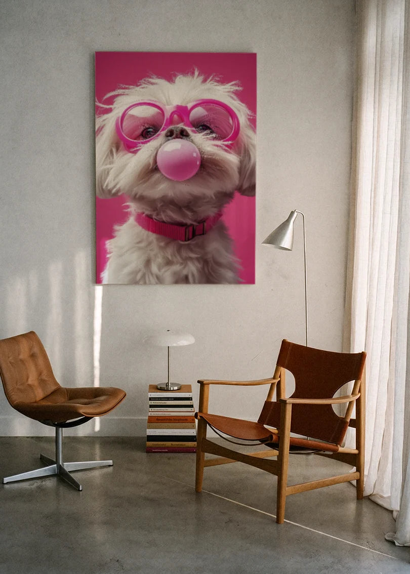 Akustikbillede med en hvid hund med tyggegummiboble og pink briller, ophængt over en lænestol ved gardinet med gulvlampe