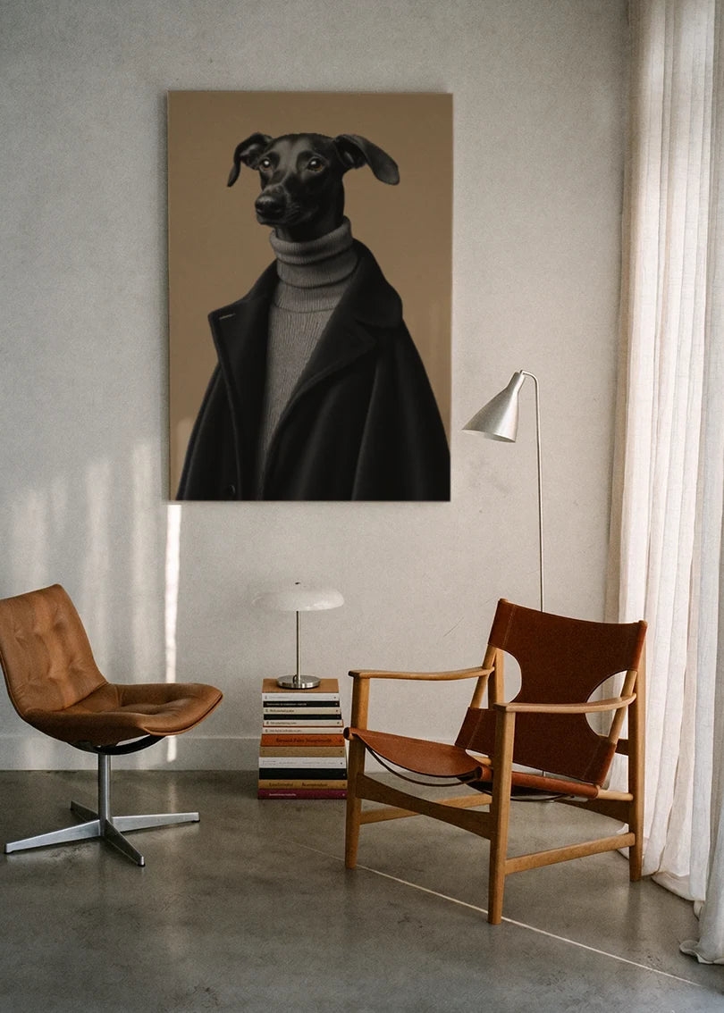 Akustikbillede med en whippet i sort rullekrave, ophængt over en lænestol ved gardinet med gulvlampe
