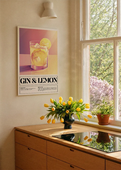 Akustikbillede med en retro cocktailplakat med Gin & Lemon, ved et køkkenvindue med gule tulipaner