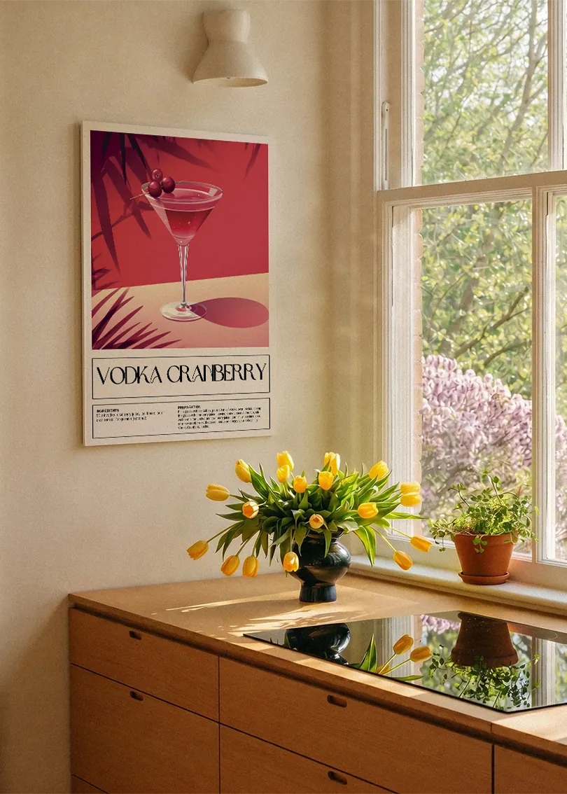 Akustikbillede med en retro cocktailplakat med Vodka Cranberry, ved et køkkenvindue med gule tulipaner