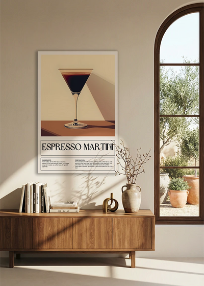 Akustikbillede med en retro cocktailplakat med Espresso Martini, over en skænk i valnød ved et buet vindue