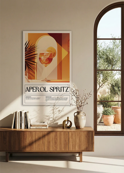 Akustikbillede med en retro cocktailplakat med Aperol Spritz, over en skænk i valnød ved et buet vindue