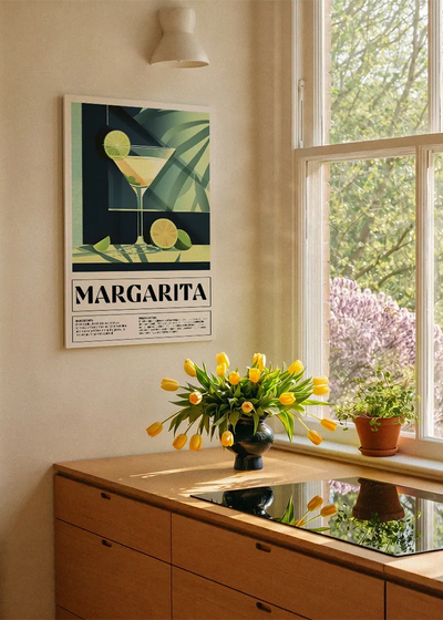Akustikbillede med en retro cocktailplakat med Margarita, ved et køkkenvindue med gule tulipaner
