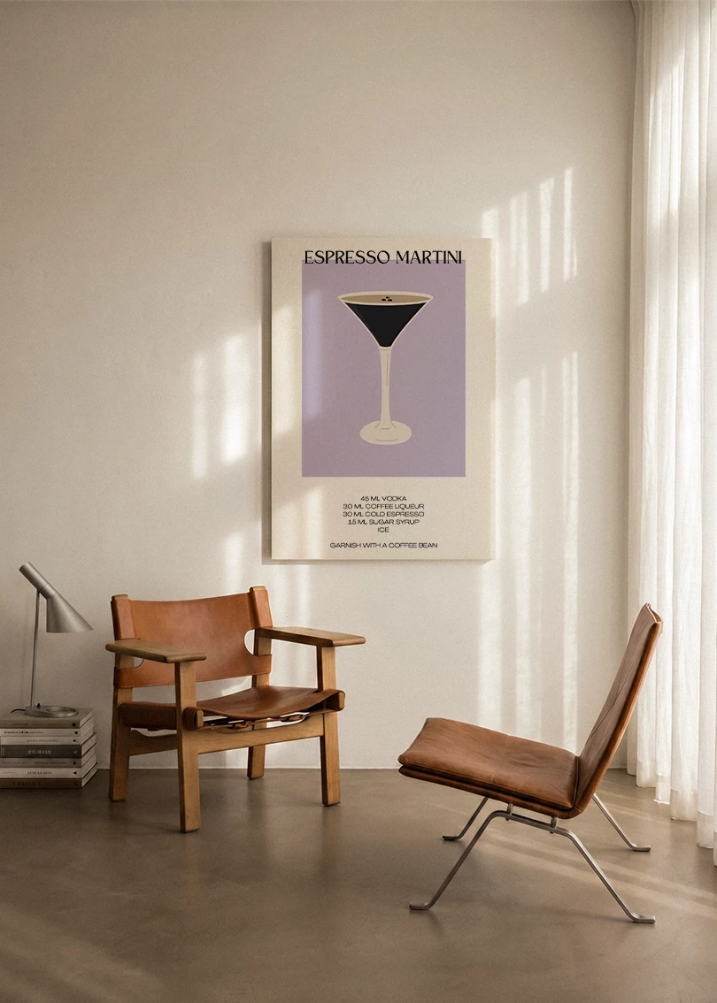 Akustikbillede med en minimalistisk cocktailplakat med Espresso Martini, ophængt over en lænestol ved gardinet