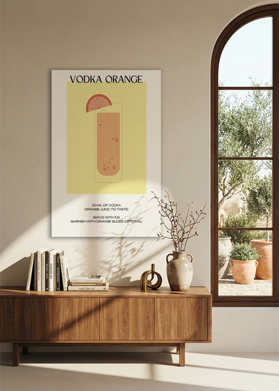 Akustikbillede med en minimalistisk cocktailplakat med Vodka Orange, over en skænk i valnød ved et buet vindue