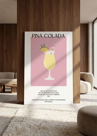 Akustikbillede med en minimalistisk cocktailplakat med Pina Colada, lænet mod vægpanel i valnød ved sofaen