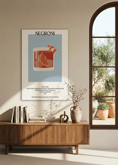 Akustikbillede med en minimalistisk cocktailplakat med Negroni, over en skænk i valnød ved et buet vindue