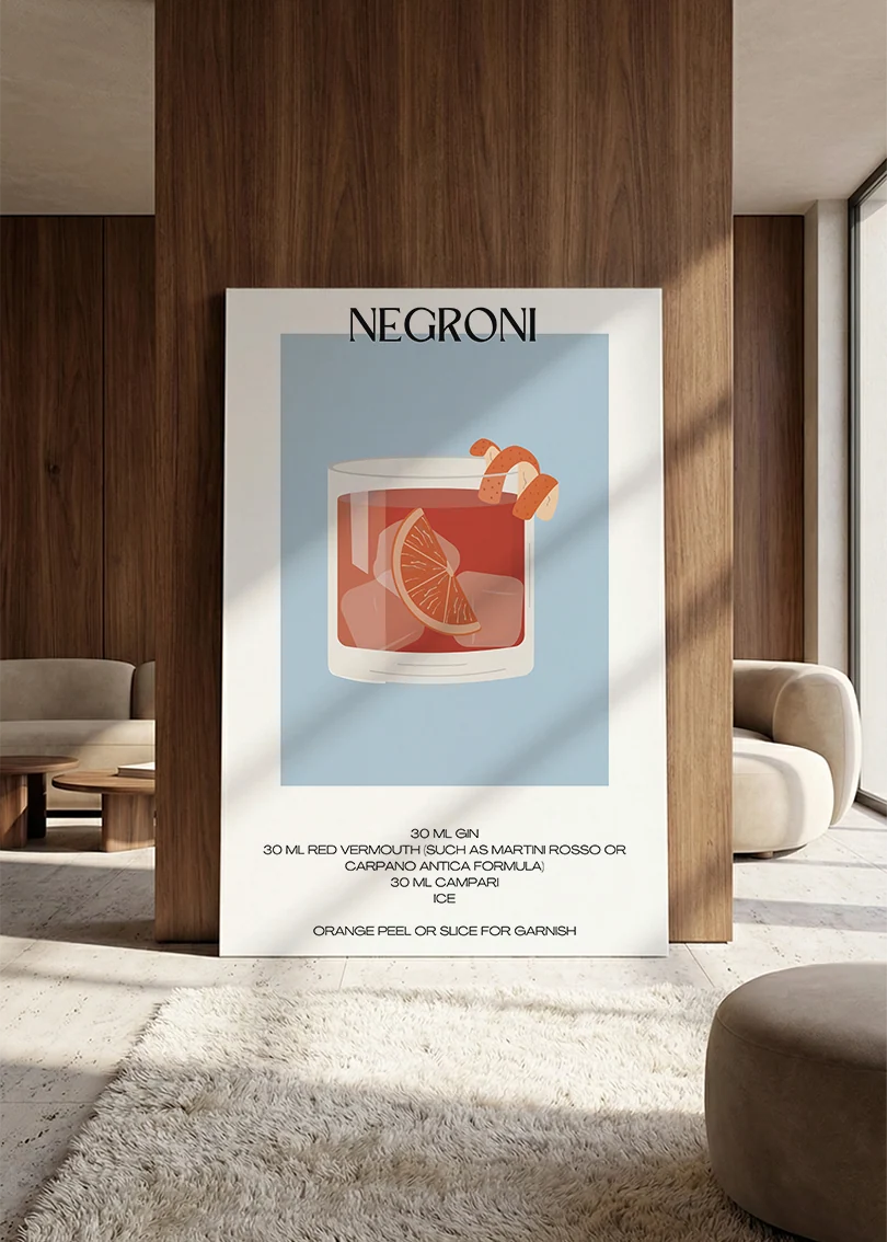 Akustikbillede med en minimalistisk cocktailplakat med Negroni, lænet mod vægpanel i valnød ved sofaen