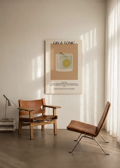 Akustikbillede med en minimalistisk cocktailplakat med Gin & Tonic, ophængt over en lænestol ved gardinet