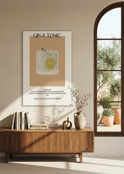 Akustikbillede med en minimalistisk cocktailplakat med Gin & Tonic, over en skænk i valnød ved et buet vindue