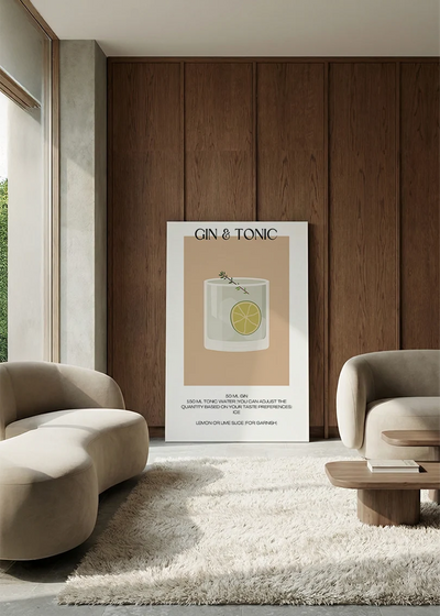 Akustikbillede med en minimalistisk cocktailplakat med Gin & Tonic, i en lounge med bugtet sofa mod vægpanel i valnød