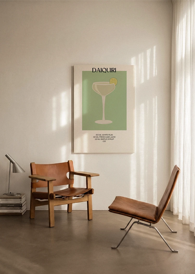 Akustikbillede med en minimalistisk cocktailplakat med Daiquiri, ophængt over en lænestol ved gardinet