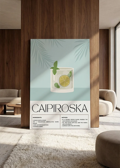 Akustikbillede med en retro cocktailplakat med Caipiroska, lænet mod vægpanel i valnød ved sofaen