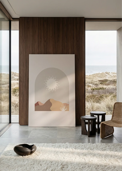Akustikbillede med en hvid sol over bjerge i beige, i stort format ved et panoramavindue med havudsigt
